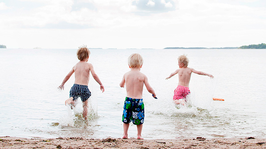 Tre barn leker i vattenbrynet.