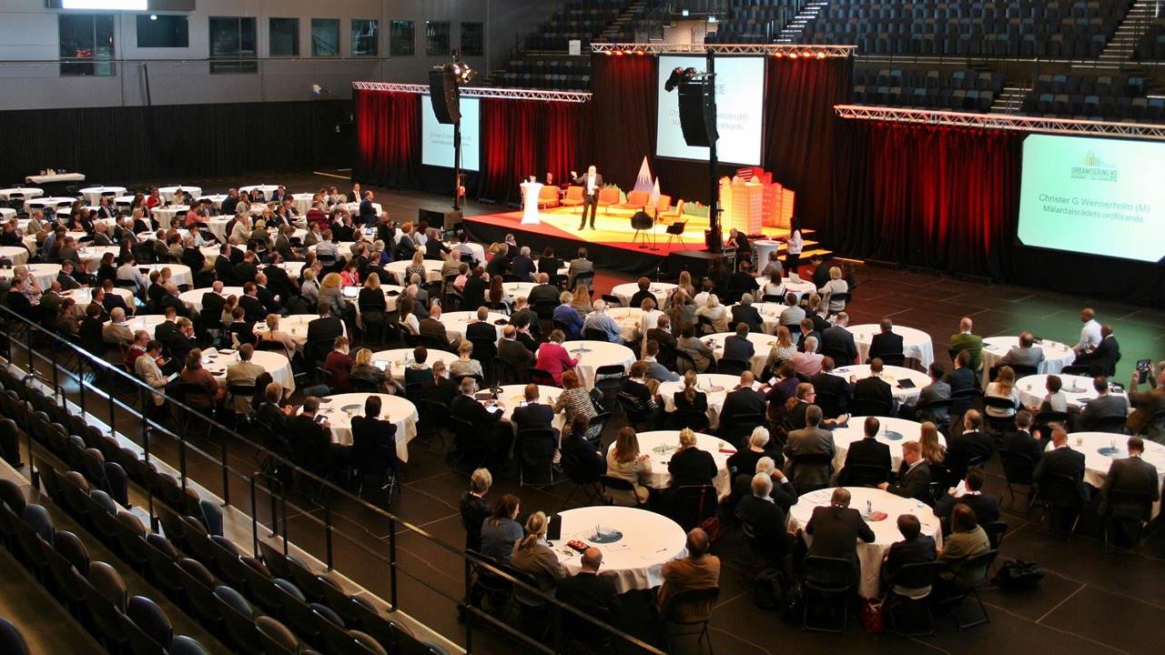 Konferens med scen och publik vid runda bord
