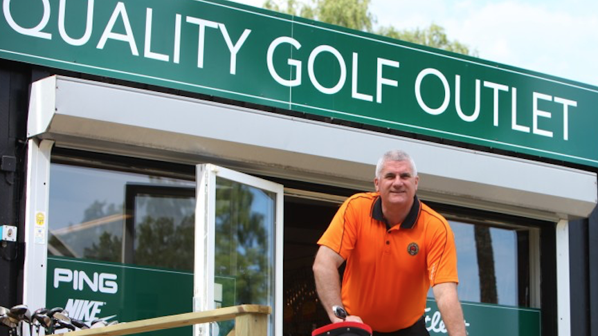 En man står framför en byggnad där det står på skylten Quality golf outlet