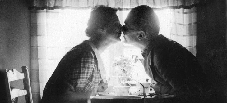 En kvinna och en man kysser varandra. Svartvitt foto i motljus.