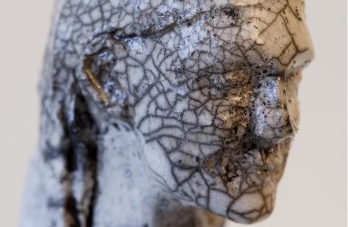 Närbild på ett ansikte i lera bränd i raku