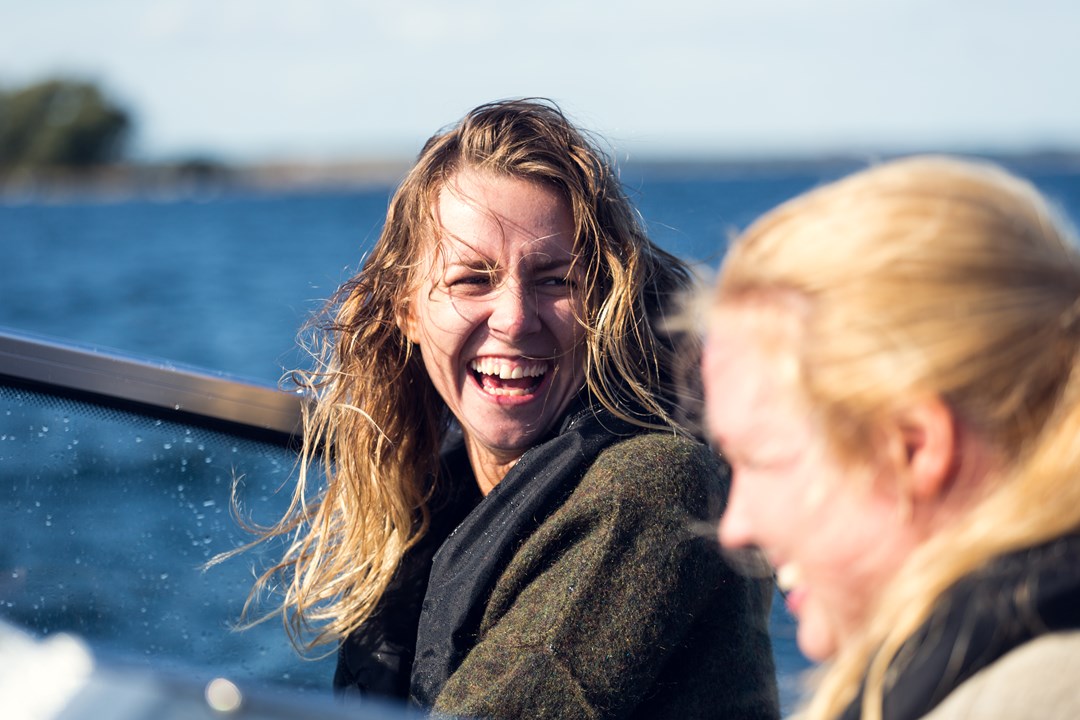 Två kvinnor som sitter och skrattar vid havet