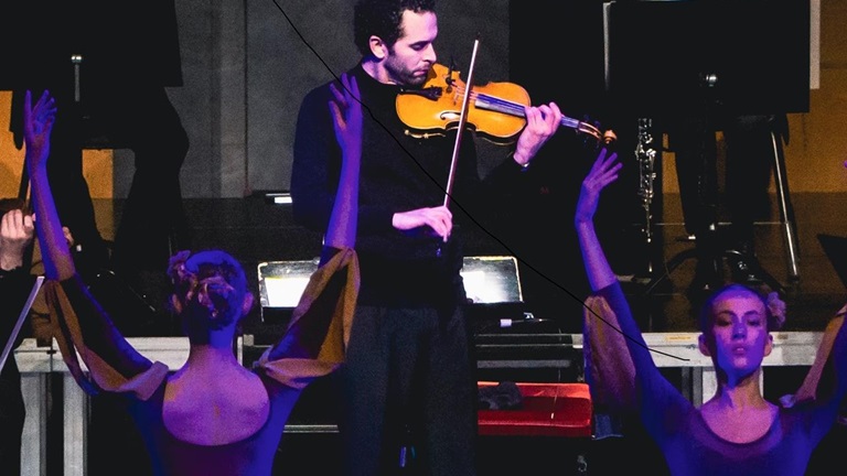 Kompositören och violinisten Mohamed Sharara spelar. Två dansare i förgrunden.