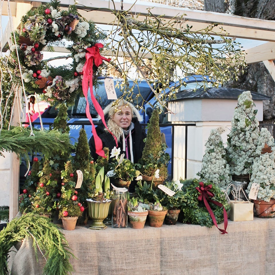 En person står och säljer blomsterarrangemang på Öster Malmas julmarknad.