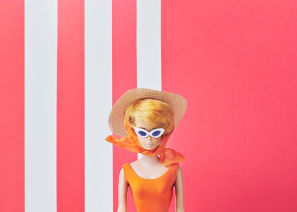 Barbiedocka med solglasögon, stråhatt, orange sjal och baddräkt