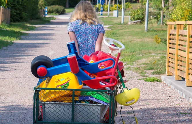 Ett barn drar en kärra full med leksaker på väg mot parkleken.