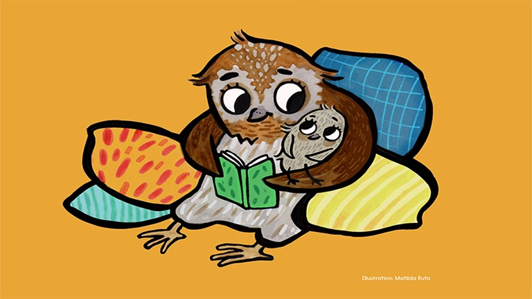 En brun uggla sitter i en hög med färgglada kuddar med vingen om en liten uggleunge och tillsammans tittar dom i en bok. Illustration: Matilda Ruta