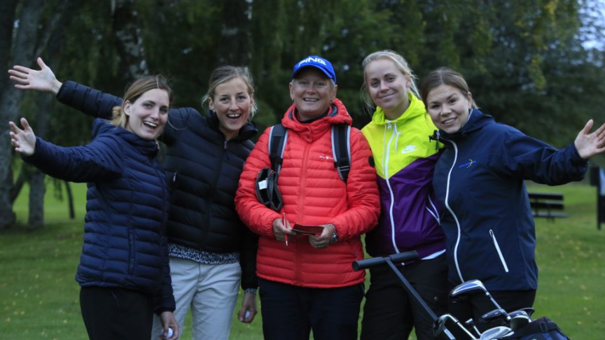 En grupp glada kvinnor står tillsammans på golfbanan 