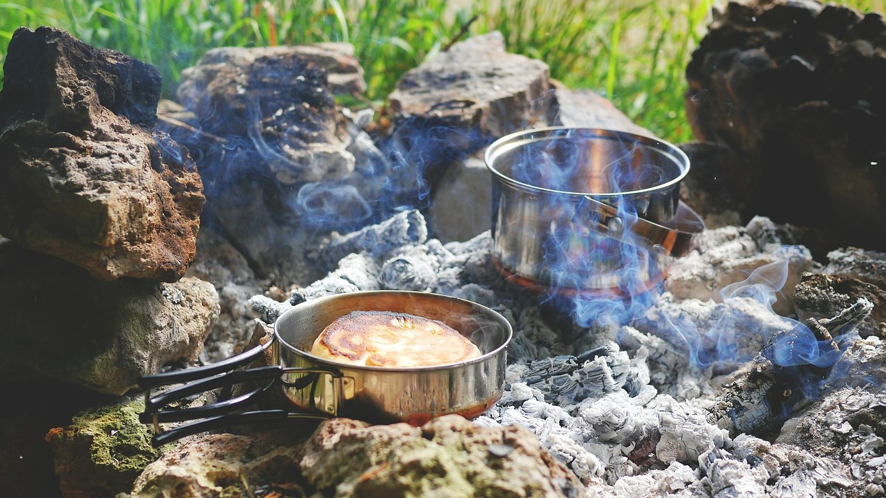 Mat som tillagas utomhus i en panna över en öppen eld.