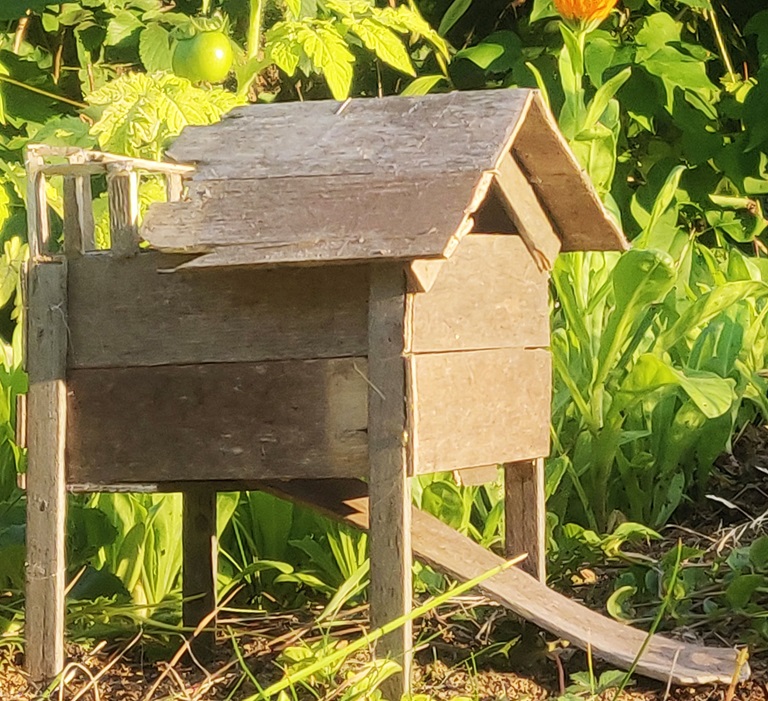Bilden visar ett miniatyrhus byggt av återbrukade träplankor