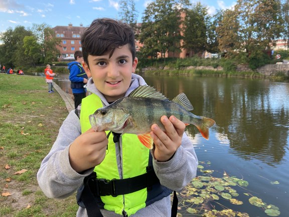 Ung pojke som stolt visar upp sin fisk