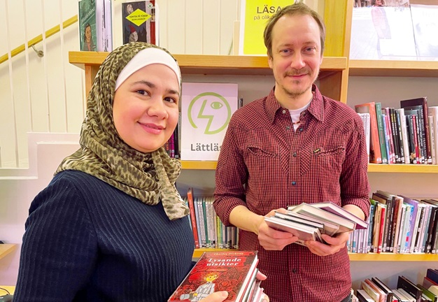 Bibliotekarierna Ghinwa och Johan framför hyllan för lättlästa böcker.