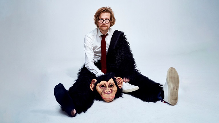 Anders "Ankan" Johansson sitter på ett golv halvt klädd i en apdräkt