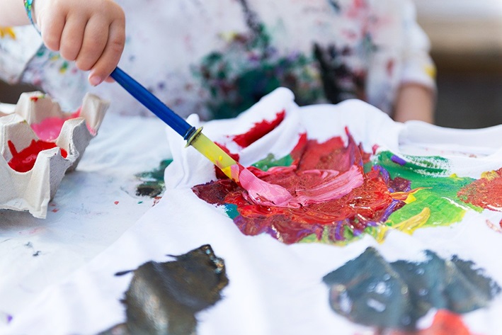 Ett barn målar en färgglad bild med oljefärger.