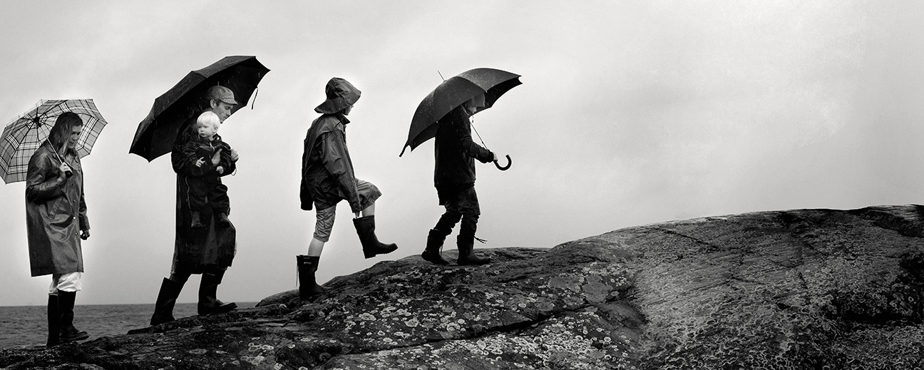 En familj med regnkläder går över en klippa.