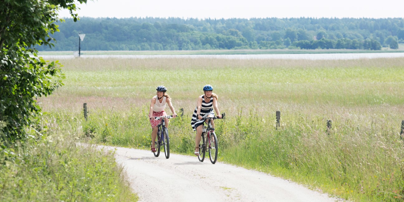 Två kvinnor cyklar på landsbygden.