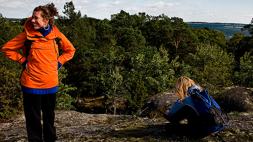 Två kvinnor uppe på en höjd i naturen.