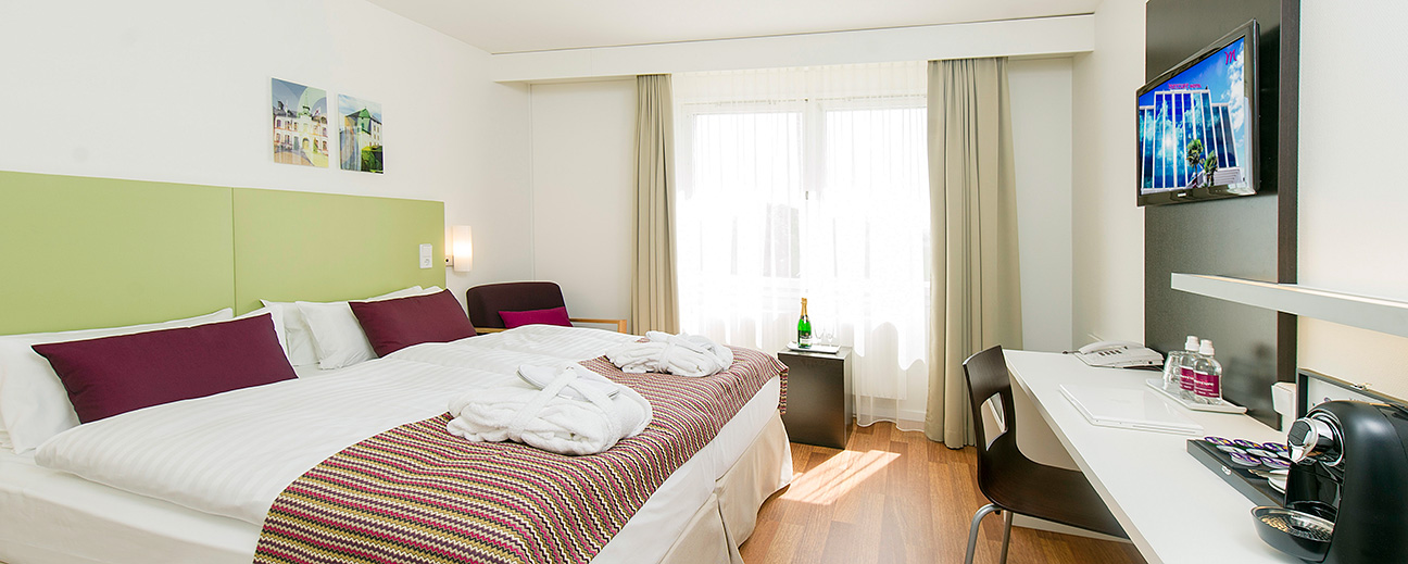 Ett prydligt hotellrum med badrockar på de bäddade sängarna.