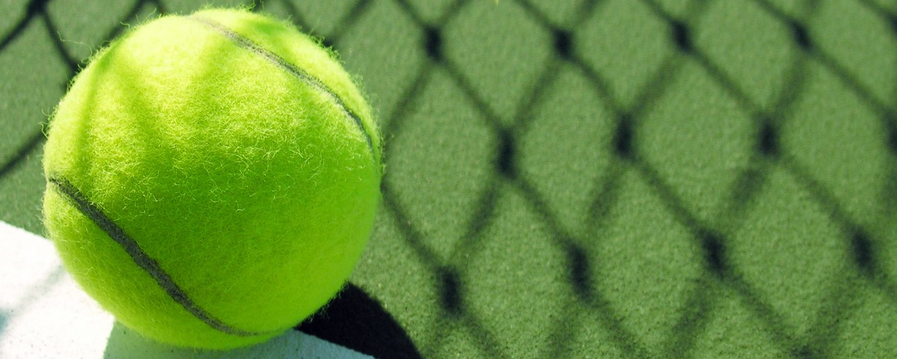 En grön tennisboll på en bana.