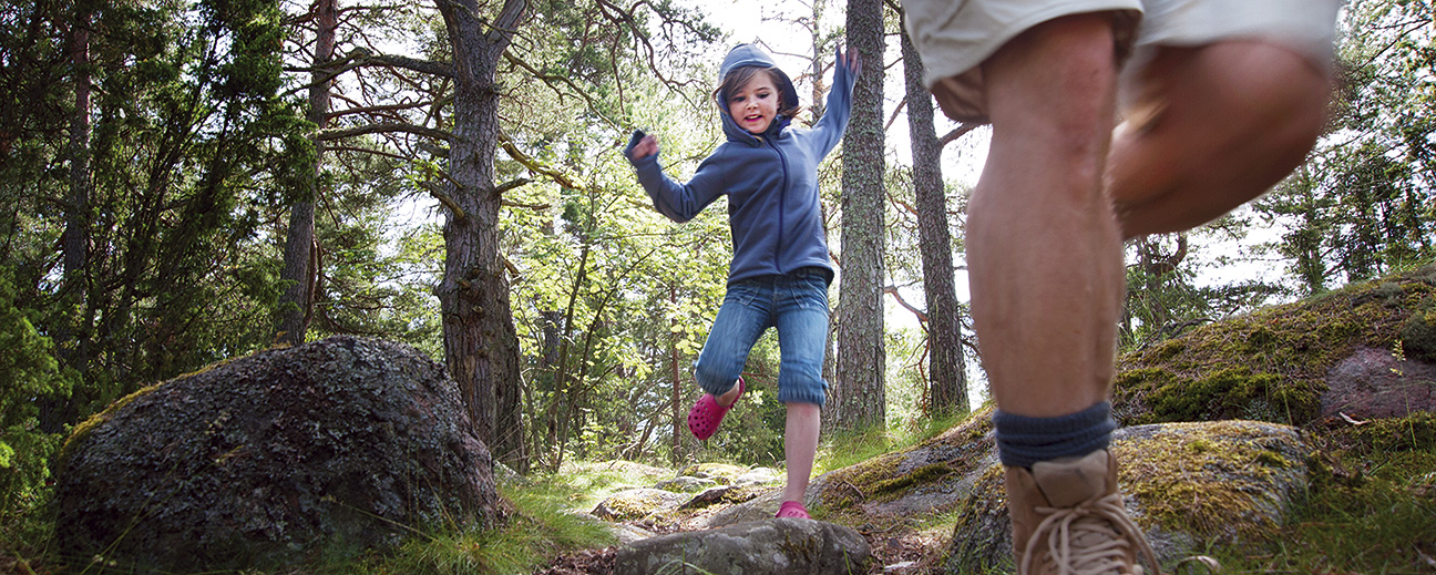 En vuxen och ett barn går nedför en skogsstig.
