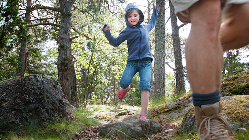 En vuxen och ett barn går nedför en skogsstig.