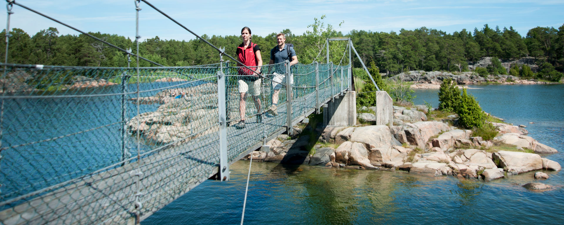 Två personer vandrar över en hängbro.