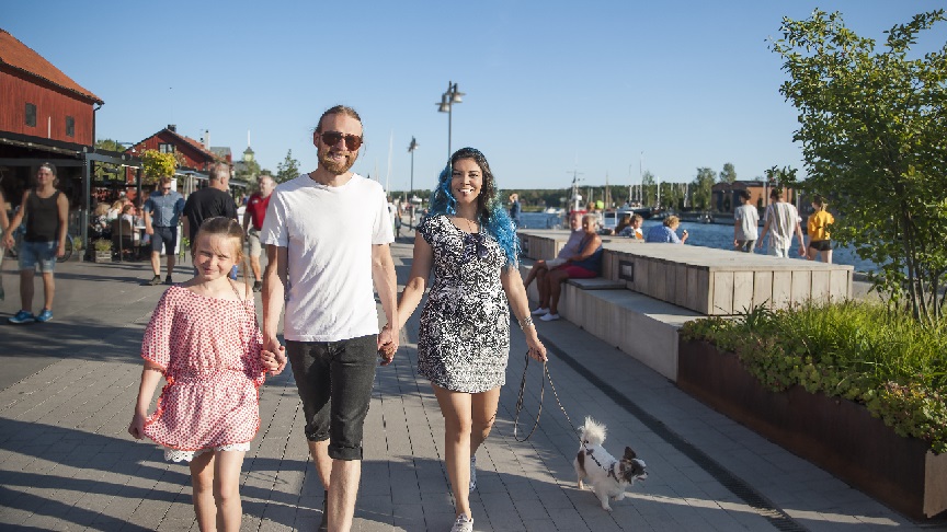 En familj promenerar med sin hund i Nyköpings folkmyllrande hamn.