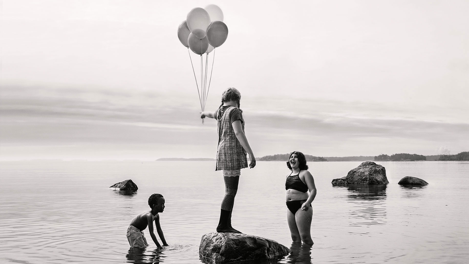 Svartvit bild med barn med ballonger i vatten