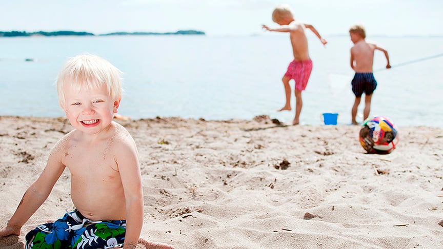 Tre pojkar som leker på en sandstrand